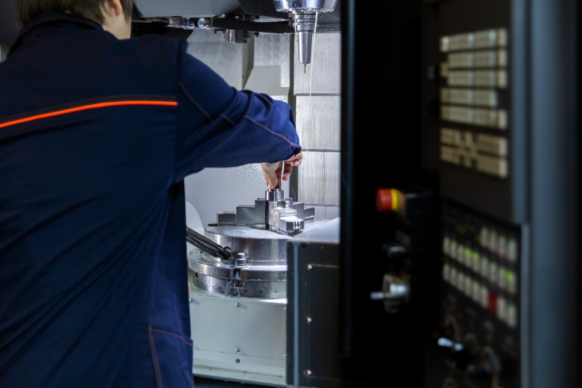 Bediener wechselt das Werkstück an einer fünfachsigen CNC-Fräsmaschine